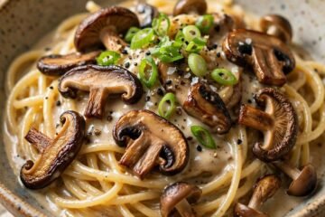 Creamy miso mushroom pasta in a shallow bowl with browned mushrooms and green onions